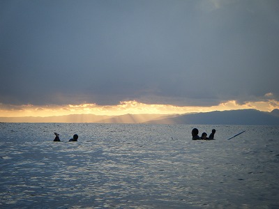 西の空に天使のはしごと波待ちする人