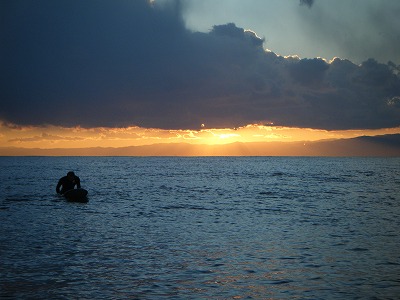 西の空に天使のはしごと波待ちする人